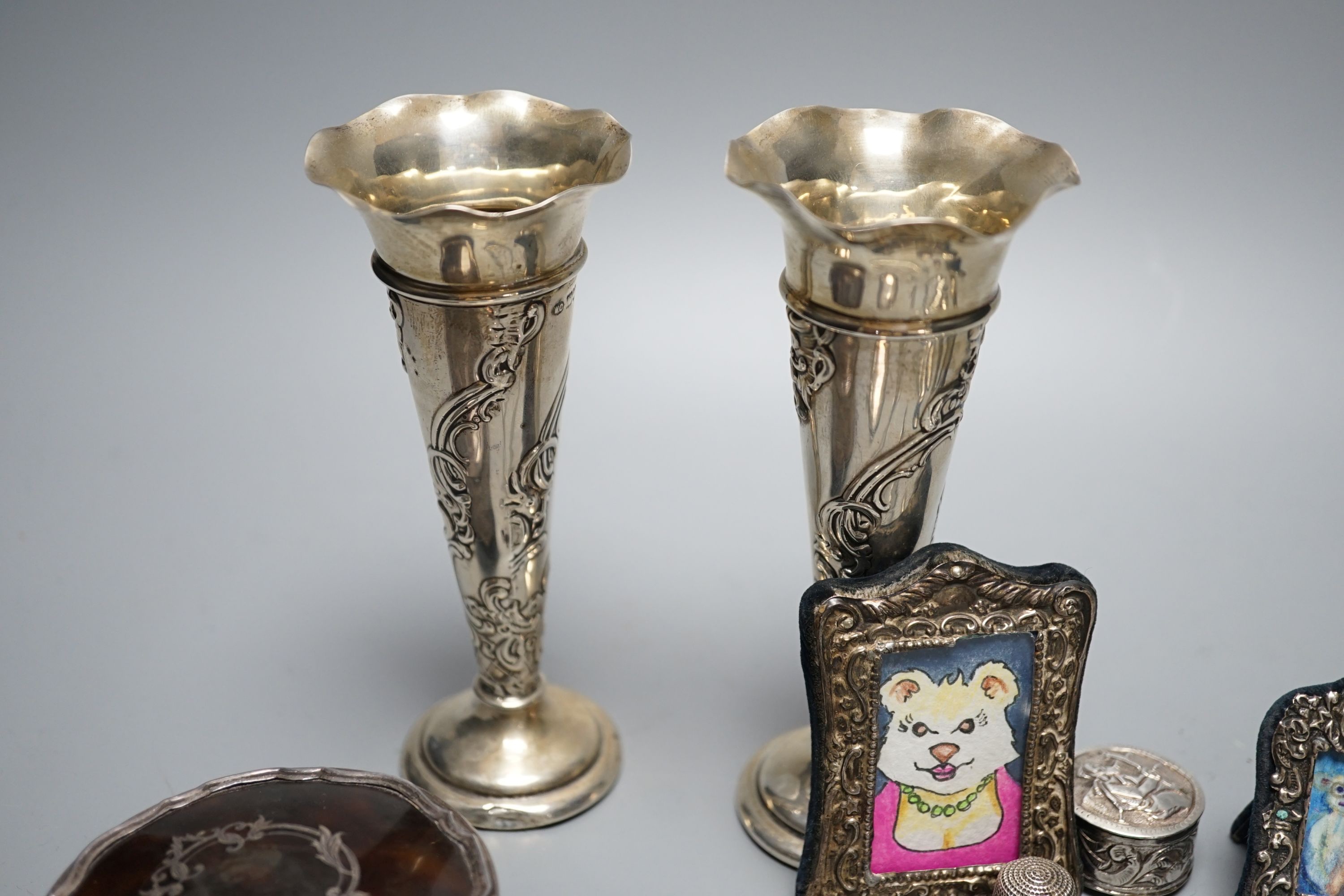 Mixed collectable silver including a pair of silver posy vases by William Comyns, 13.6cm, a George V silver and tortoiseshell trinket box, two small silver mounted photograph frames, four silver thimbles, compact, pill b